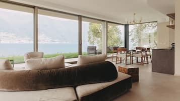 Una sala de estar moderna con un sofá grande, comedor y vista a un lago.