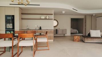 A modern living room with a dining area, kitchen, and a bedroom.