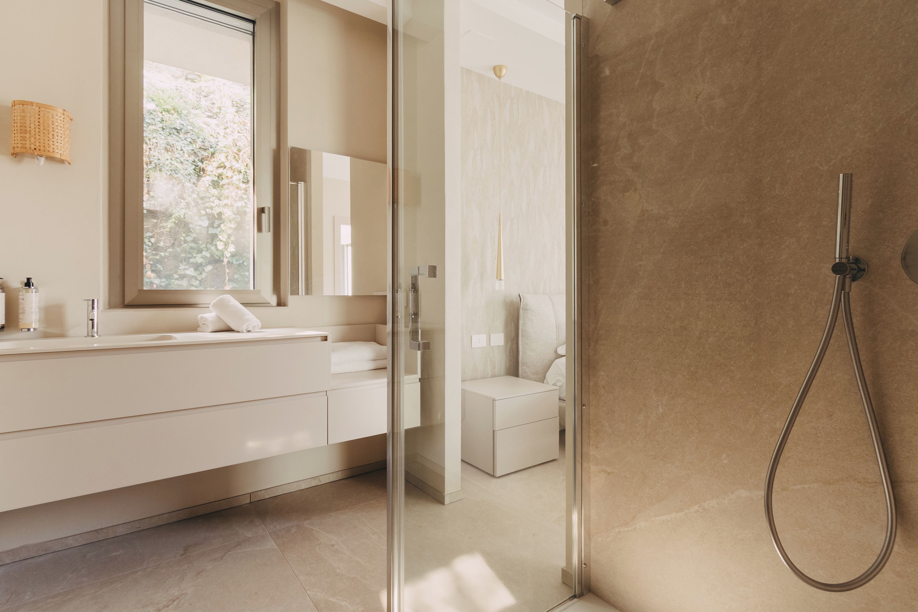 A modern bathroom with a glass shower enclosure, a large mirror, and a white vanity.