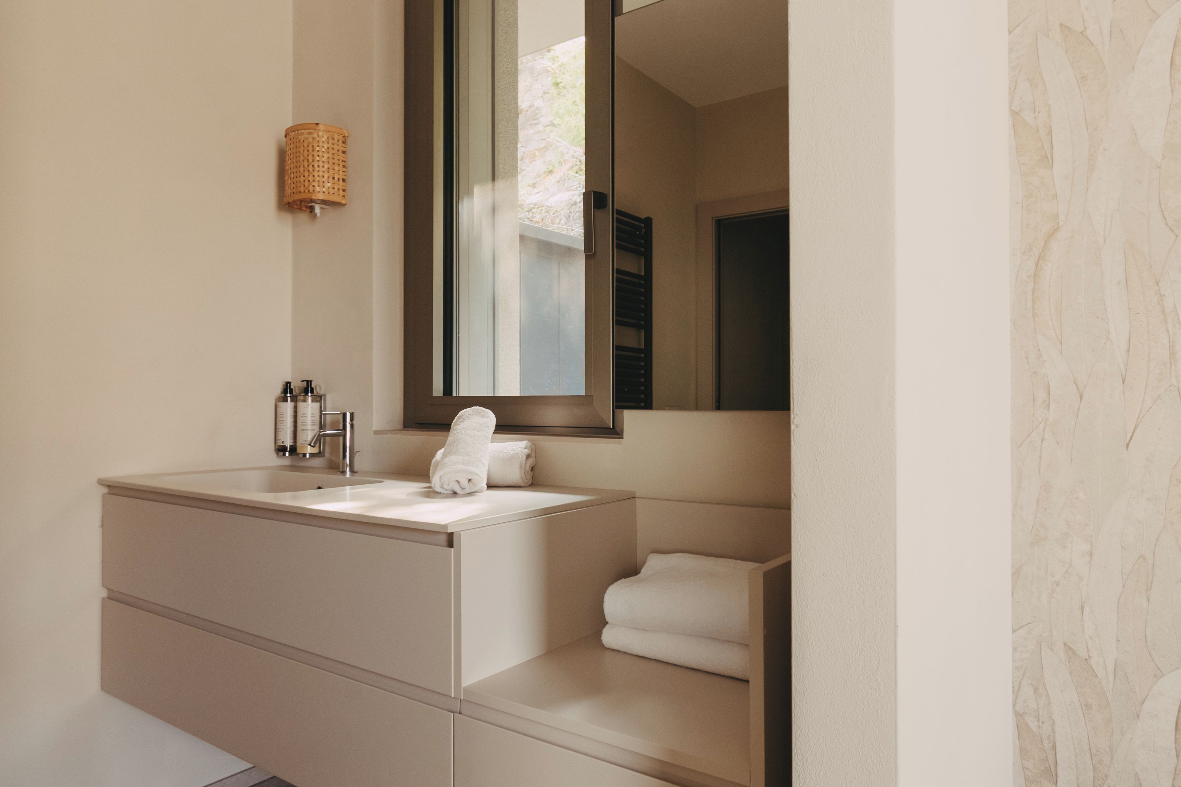 A modern bathroom with a large mirror, a sink, and a towel rack.