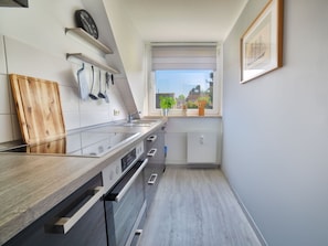 A modern kitchen with a wooden countertop, stainless steel appliances, and a window with a view. - Holiday Apartment With 2 Bedrooms (Heiligenhafen)