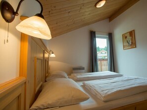 A room with two beds, wooden headboard, a window with curtains, and a wall-mounted lamp. - Cabin in Annaberg With Swimming Pool (Annaberg-Lungoetz)