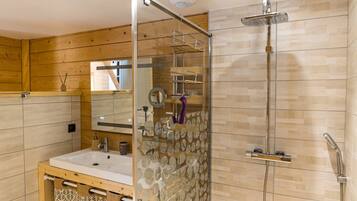 A modern bathroom with a glass-enclosed shower, a wooden vanity, and a mirror.