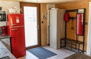 A compact kitchen with a red refrigerator, wooden walls, a bench, and a door leading outside. - Chalet 'Des Sources, Avec Spa' with Mountain View, Private Terrace and Wi-Fi (Ramonchamp)