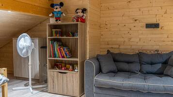 Una habitación acogedora con una estantería de madera, un sofá gris y dos peluches encima.