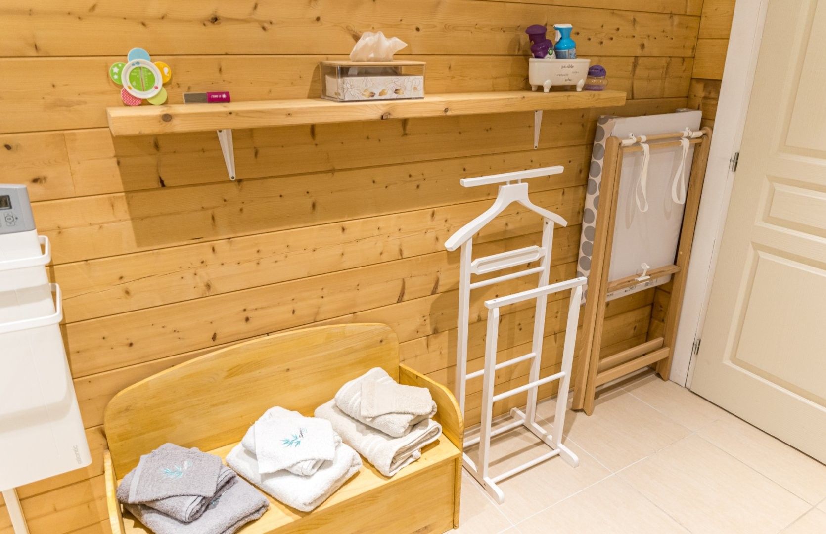 Ein Zimmer mit Holzwand, einem hölzernen Bett, einem weißen Handtuchhalter und einem Ablagebereich für Toilettenartikel.