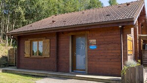 Une cabane en bois avec un toit en tuiles, une porte et une petite enseigne.