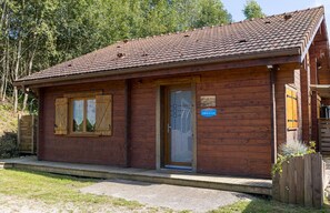 A wooden cabin with a tiled roof, a door, and a small sign.
