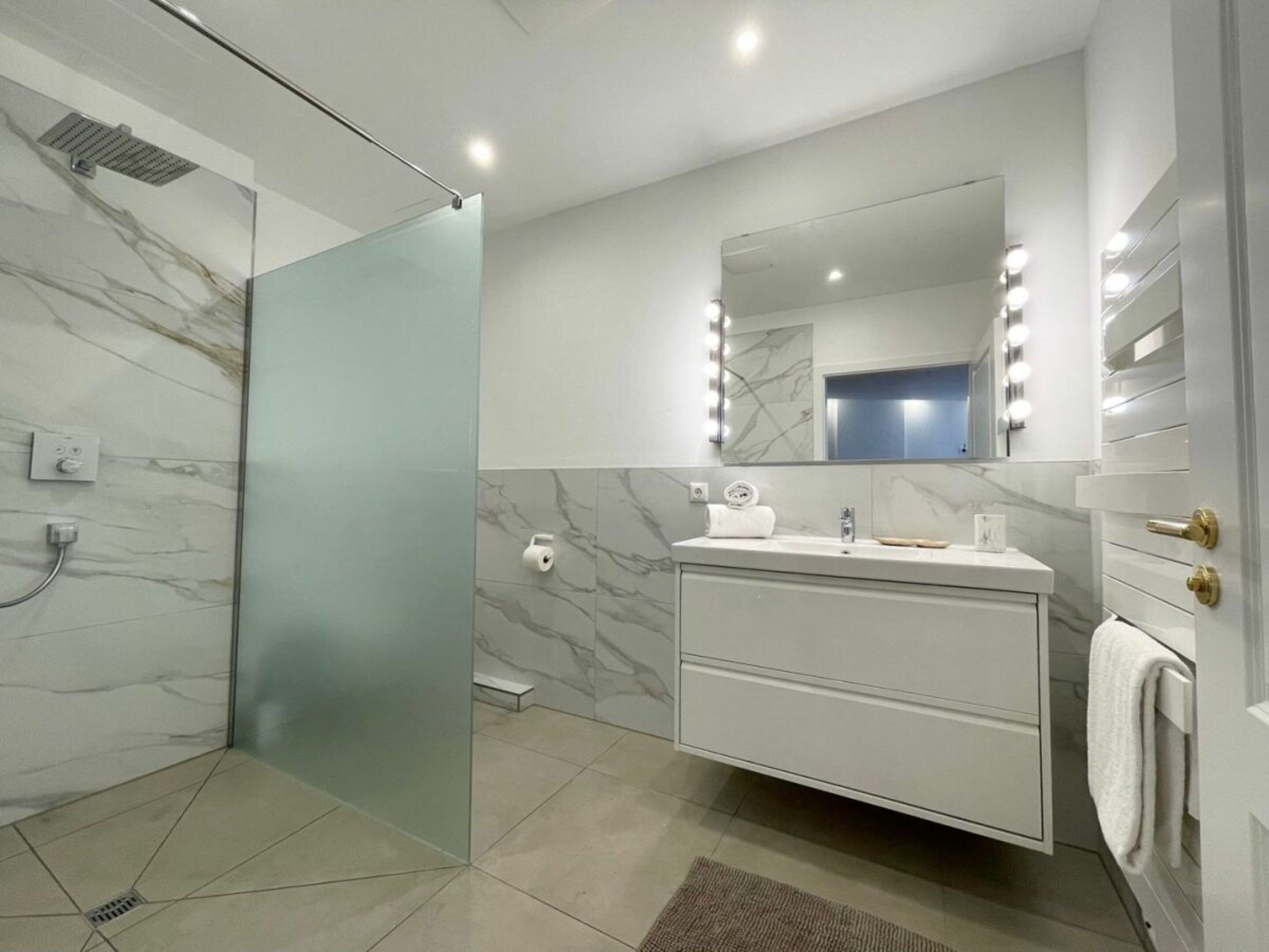 A modern bathroom with a glass shower enclosure, a vanity with a mirror, and a towel rack.