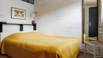 Ein Zimmer mit einem Bett, einem Sessel, einem Bild an der Wand und einer Tür.