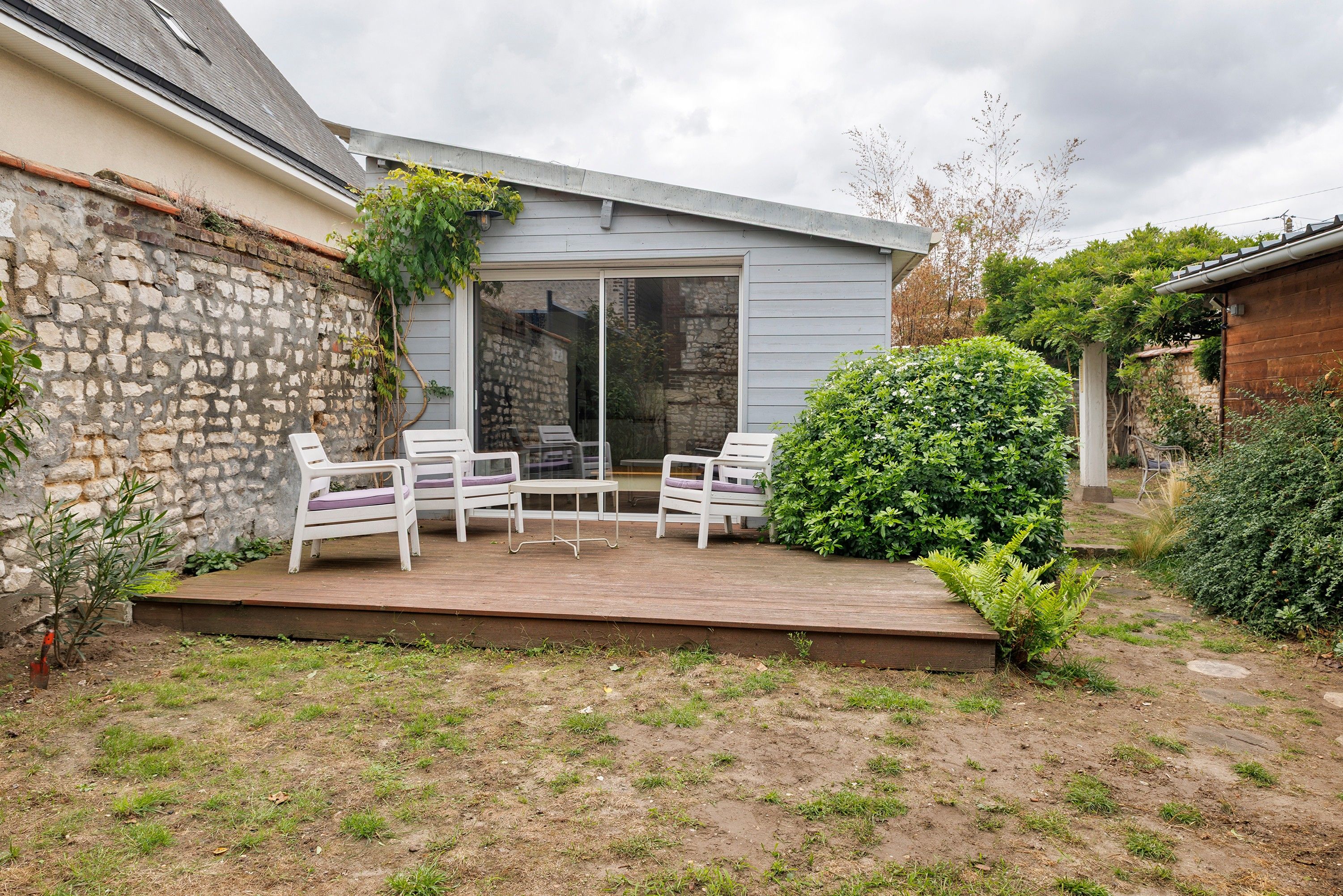 Une terrasse avec des sièges d’extérieur, un mur en pierre et une plateforme en bois.