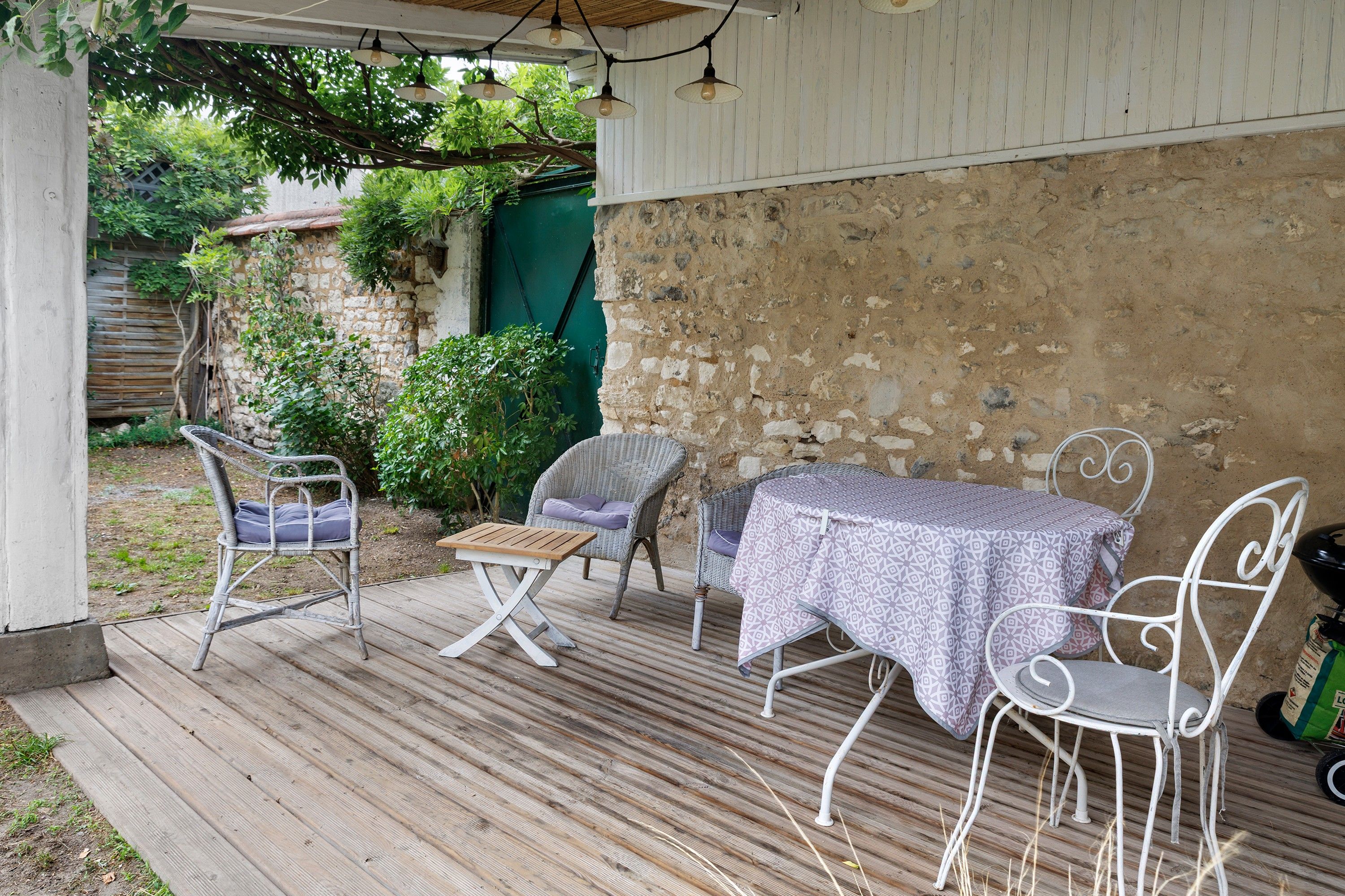 An outdoor patio with wicker furniture, a wooden table, and a metal chair.