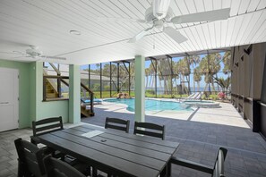 An outdoor patio with a pool, lounge chairs, and a table. - Oasis Incredible River Front/Ocean Access w/Dock (Melbourne Beach)