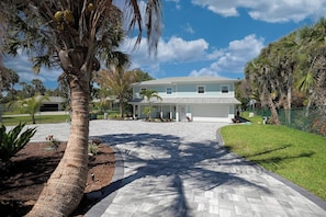 A two-story house with a paved driveway leading to a covered porch. - Oasis Incredible River Front/Ocean Access w/Dock (Melbourne Beach)