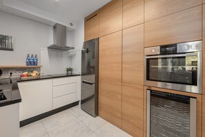 Eine moderne Küche mit Edelstahlgeräten, einer Wand aus Holzschränken und einer Arbeitsfläche mit Obst und Flaschen.