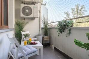 Ein Balkon mit Tisch, Stühlen, einem Ventilator und Topfpflanzen.