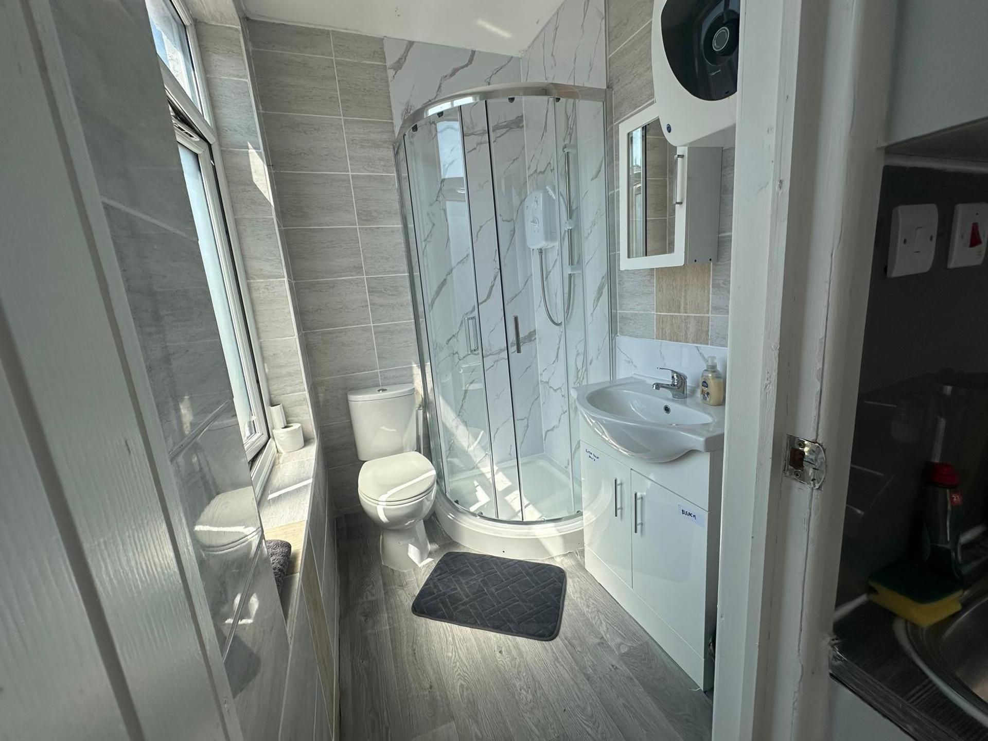 A compact bathroom with a shower enclosure, toilet, sink, and storage cabinets.