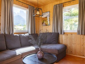 A modern living room with a sectional sofa, a round coffee table, and a vase with dried plants. - Cabin in Annaberg With Swimming Pool (Annaberg-Lungoetz)