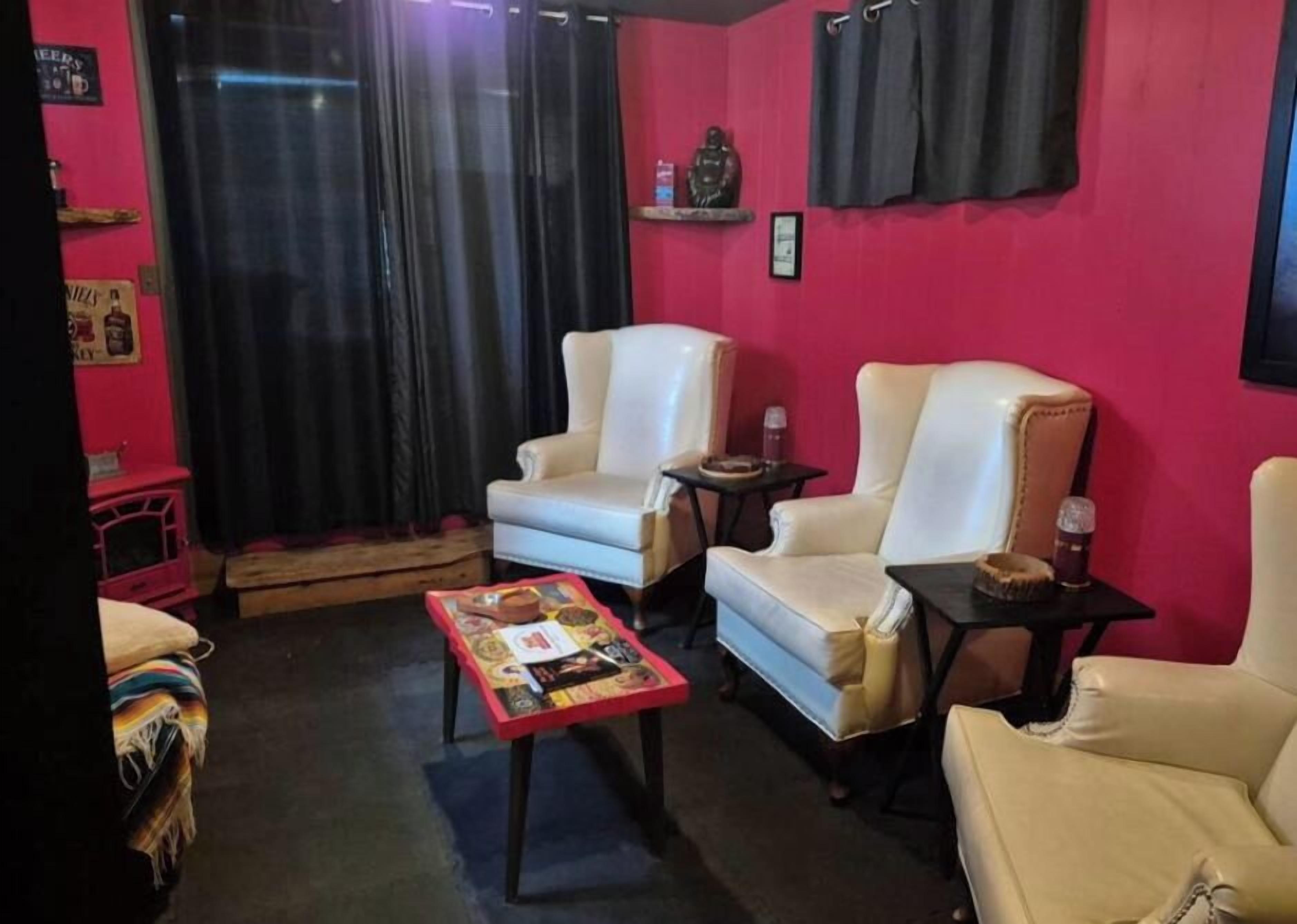 A living room with two white leather sofas, a small coffee table, and a red table with various items.