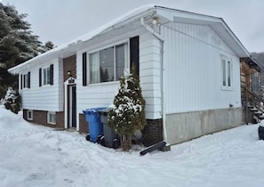 Une maison de plain-pied avec un toit à pignon, une porte d’entrée et un petit porche.
