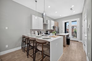 A modern kitchen with a central island, bar stools, and a view of the outside.