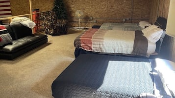 A room with a bed, a couch, a small table, and a fan.