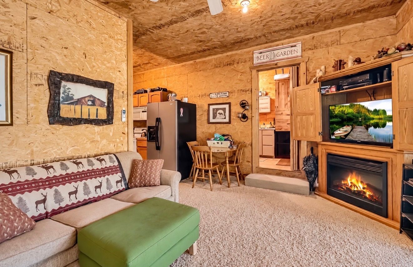 Ein gemütliches Wohnzimmer mit Kamin, einem Essbereich und einer durch einen offenen Durchgang einsehbaren Küche.