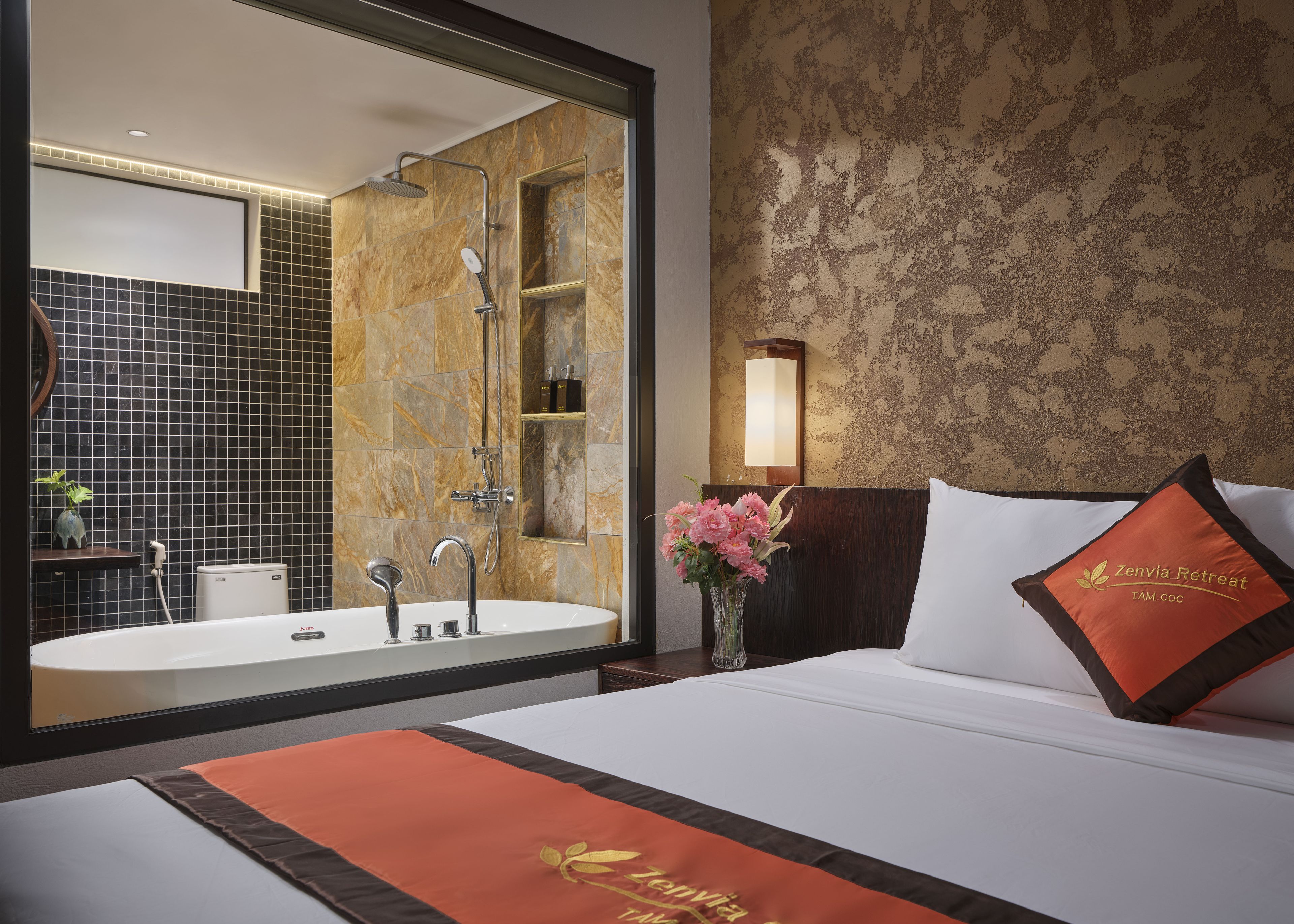 A hotel room with a large bed, a bathroom with a bathtub, and a mirror.
