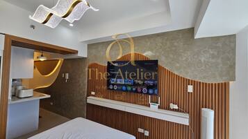Habitación de hotel moderna con una cama, tocador con espejo, televisor montado en la pared y una lámpara de techo original.