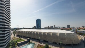 A large, modern stadium with a unique curved roof, surrounded by urban buildings and a clear sky. - Luxe Private Studio - Balcony & View (Bratislava III)