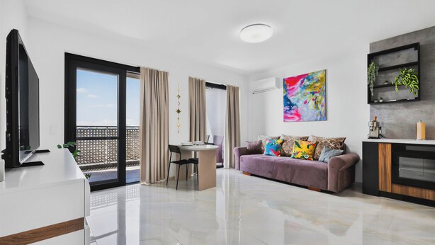 A modern living room with a sofa, a dining area, and a kitchen area. - Luxe Private Studio - Balcony & View (Bratislava III)