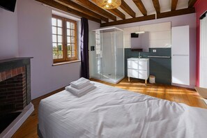 Una camera da letto con un letto, un camino, una doccia e un bagno con lavandino e specchio.