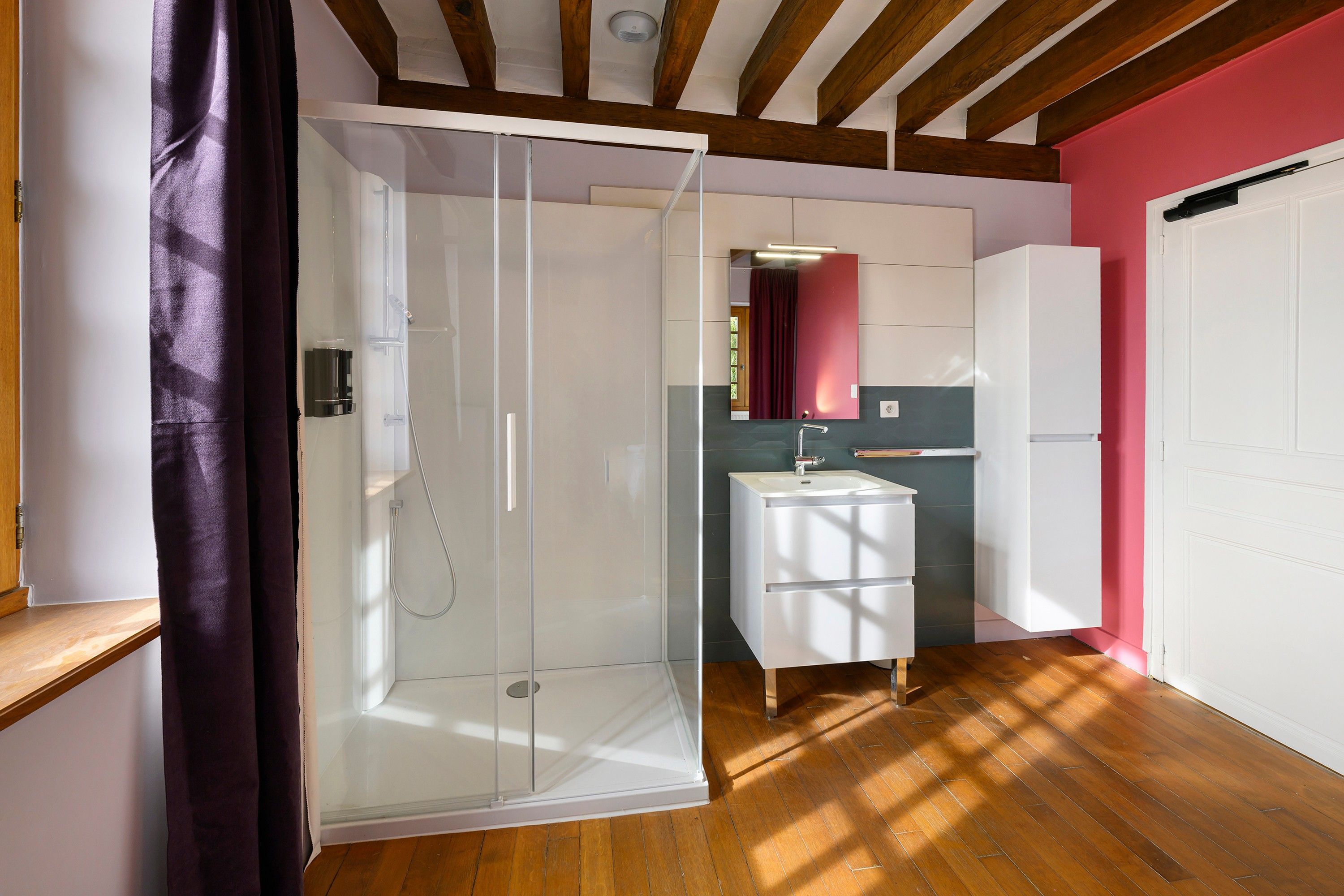 Ein modernes Badezimmer mit einer Duschkabine aus Glas, einem weißen Waschbecken und einem Spiegel darüber.