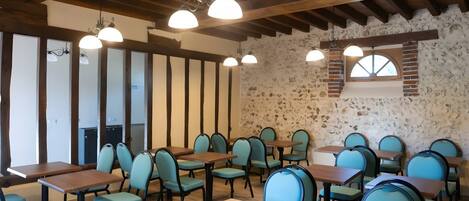 Un interno ristorante con travi in legno, pareti in pietra e diversi tavoli e sedie.
