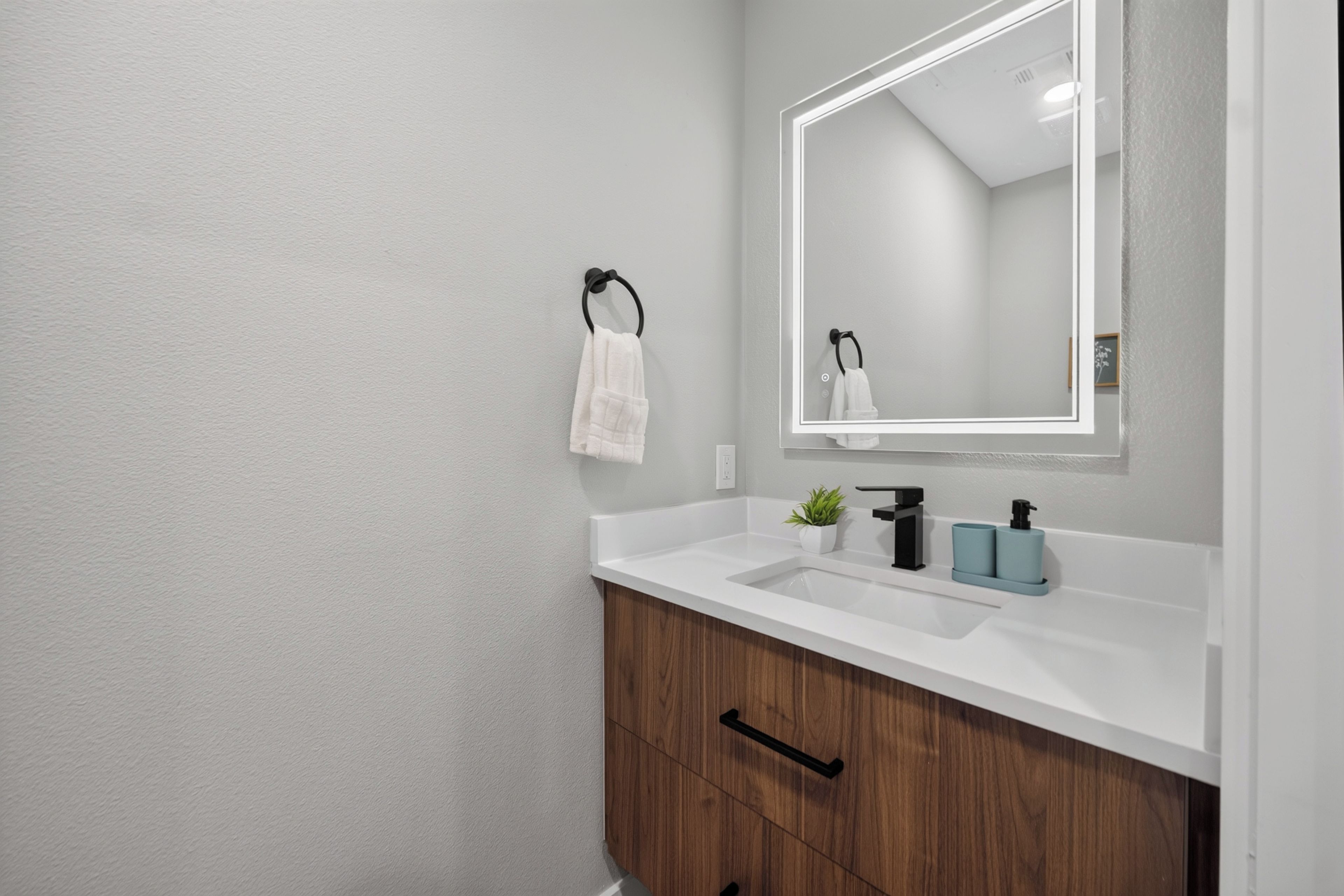 A bathroom with a white sink, wooden cabinet, and a mirror.