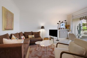 A living room with a brown sofa, a white coffee table, and a TV on a stand. - Apartment '3 Pièces Cannes' with Shared Terrace, Wi-Fi and Air Conditioning (Cannes)
