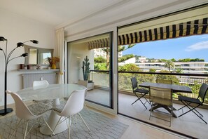 Ein modernes Wohnzimmer mit einem Glastisch, weißen Stühlen, einer Couch und einem großen Fenster.