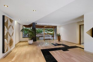 A spacious lobby with a modern design, featuring a large potted plant, a decorative wall, and a clear view of an outdoor area through glass doors. - Apartment '3 Pièces Cannes' with Shared Terrace, Wi-Fi and Air Conditioning (Cannes)