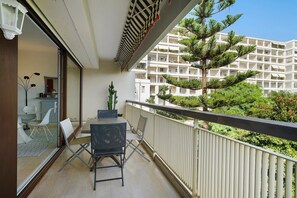 A balcony with a table and chairs, a potted plant, and a view of a multi-story building with balconies. - Apartment '3 Pièces Cannes' with Shared Terrace, Wi-Fi and Air Conditioning (Cannes)