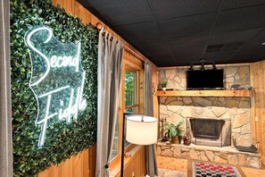 A cozy room with a stone fireplace, a neon sign reading 'Second Floor,' and a television mounted above the fireplace. - Foliage Heaven! A+ Location! Cabin w/Private HTub (Sevierville)