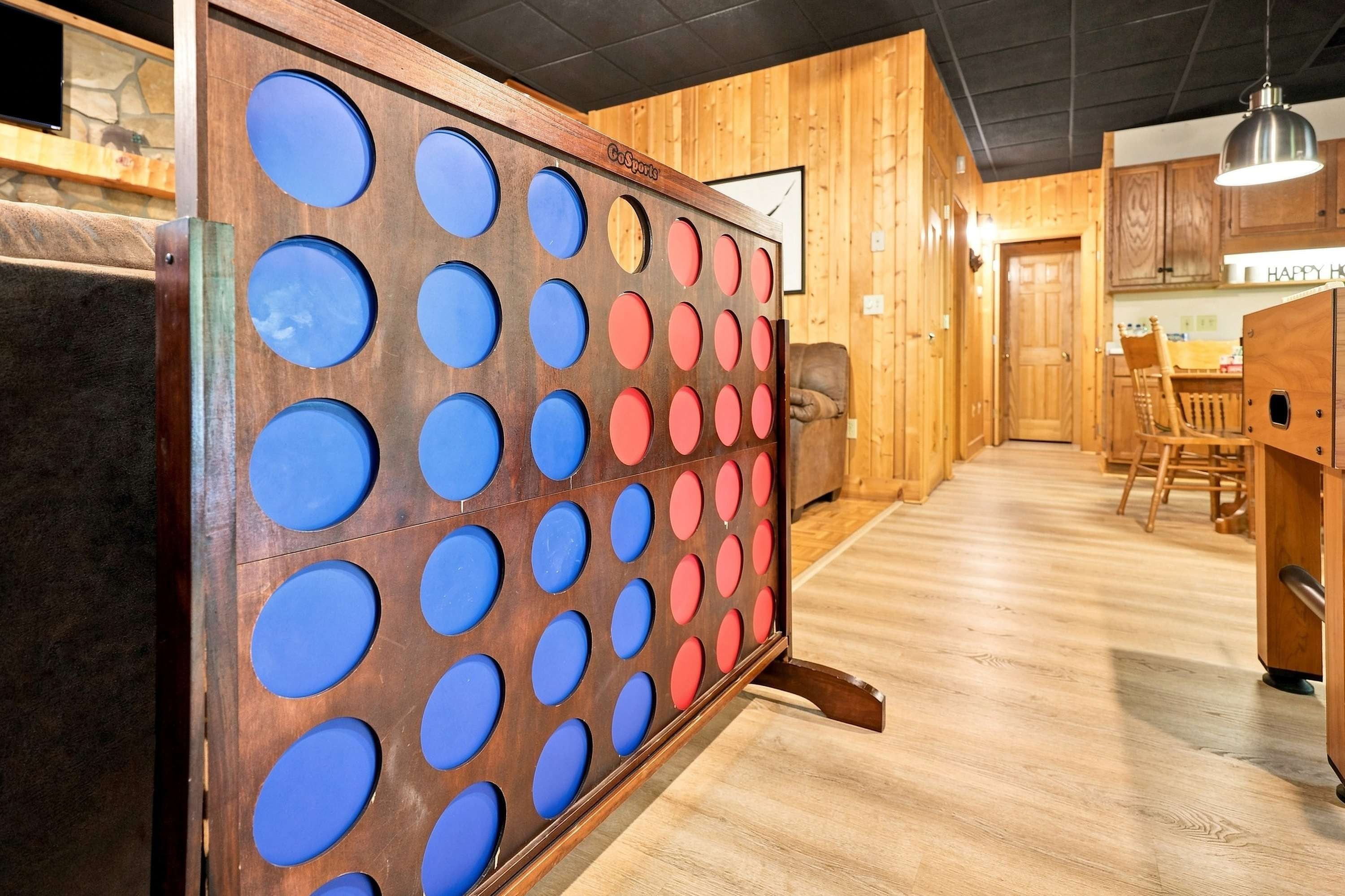 Een houten interieur met een wandspel, een houten vloer en een eethoek met stoelen en een tafel.