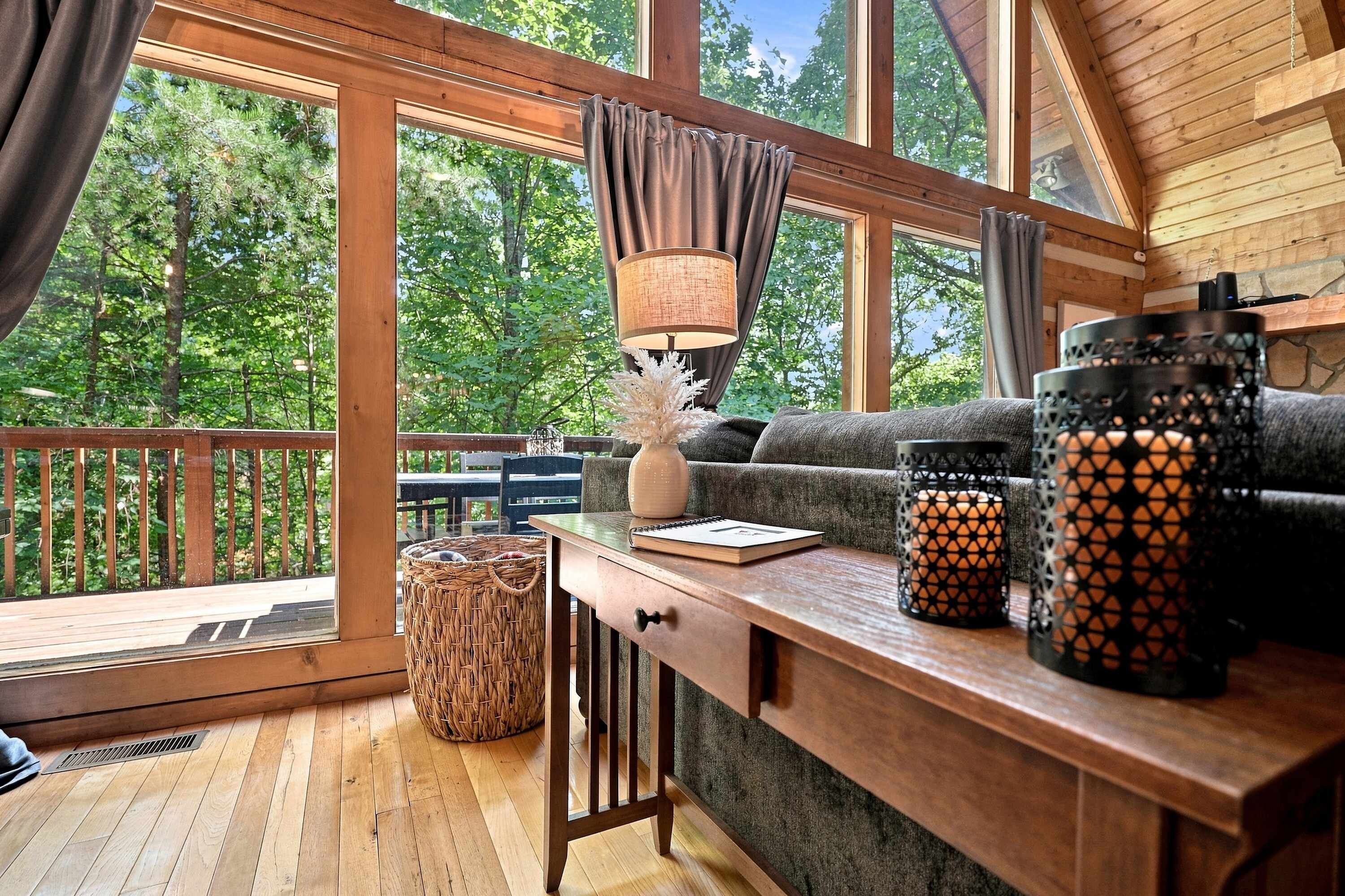 A cozy cabin interior with a wooden deck, a sofa, a table with a lamp, and decorative items.