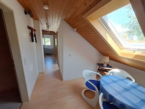 A room with a sloped ceiling, a skylight, a dining area with a table and chairs, and a hallway leading to another room. - Apartment 'Fewo Ruthe' (Wehr)