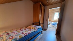 A single bed with a colorful bedspread in a room with wooden flooring and a wooden ceiling. - Apartment 'Fewo Ruthe' (Wehr)