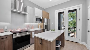 Une cuisine moderne dotée d’appareils électroménagers en acier inoxydable, d’armoires en bois et d’un grand îlot central.