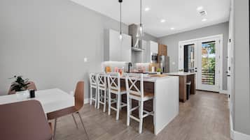 Une cuisine moderne avec des meubles blancs, un îlot central et des luminaires suspendus.