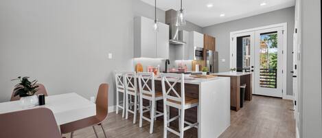 A modern kitchen with white cabinetry, a central island, and pendant lighting.