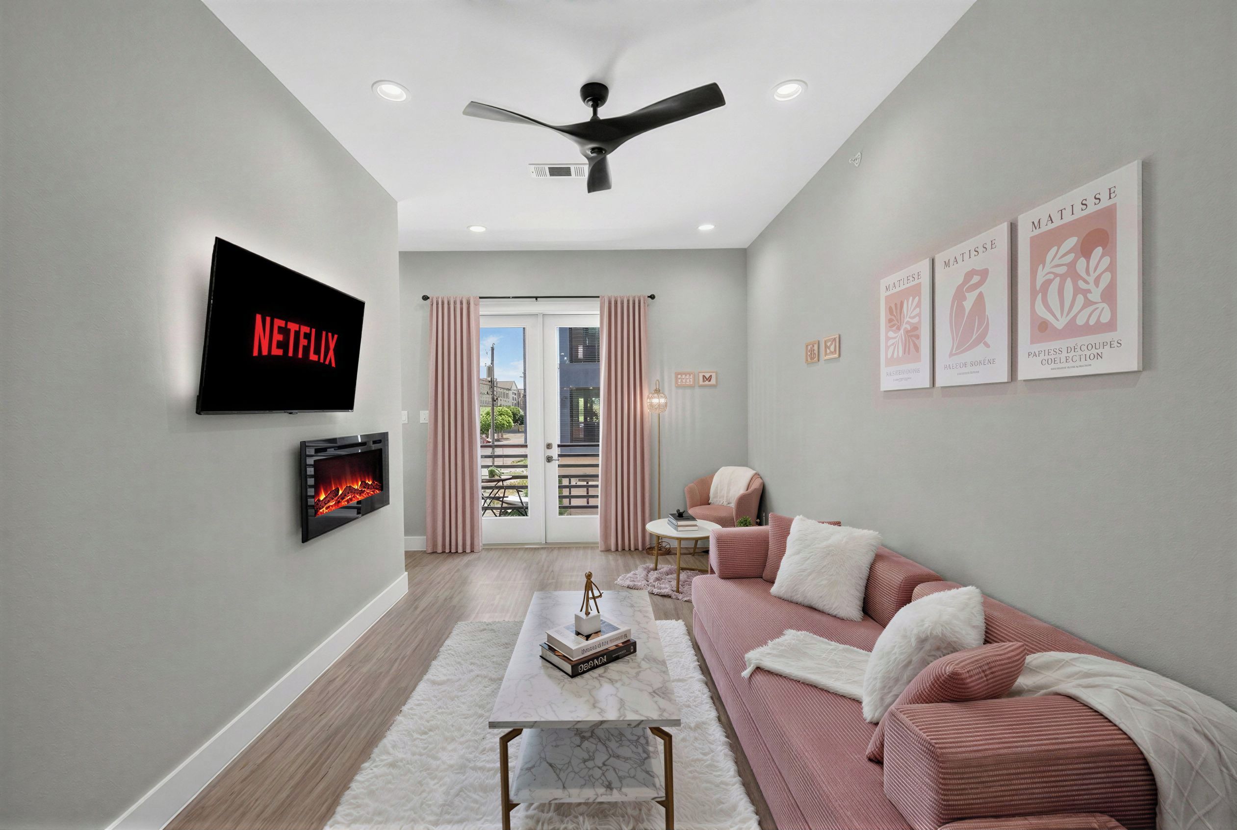 Chic lounge with pink accents, fireplace, TV, and private balcony light