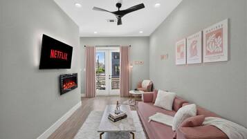 Chic lounge with pink accents, fireplace, TV, and private balcony light