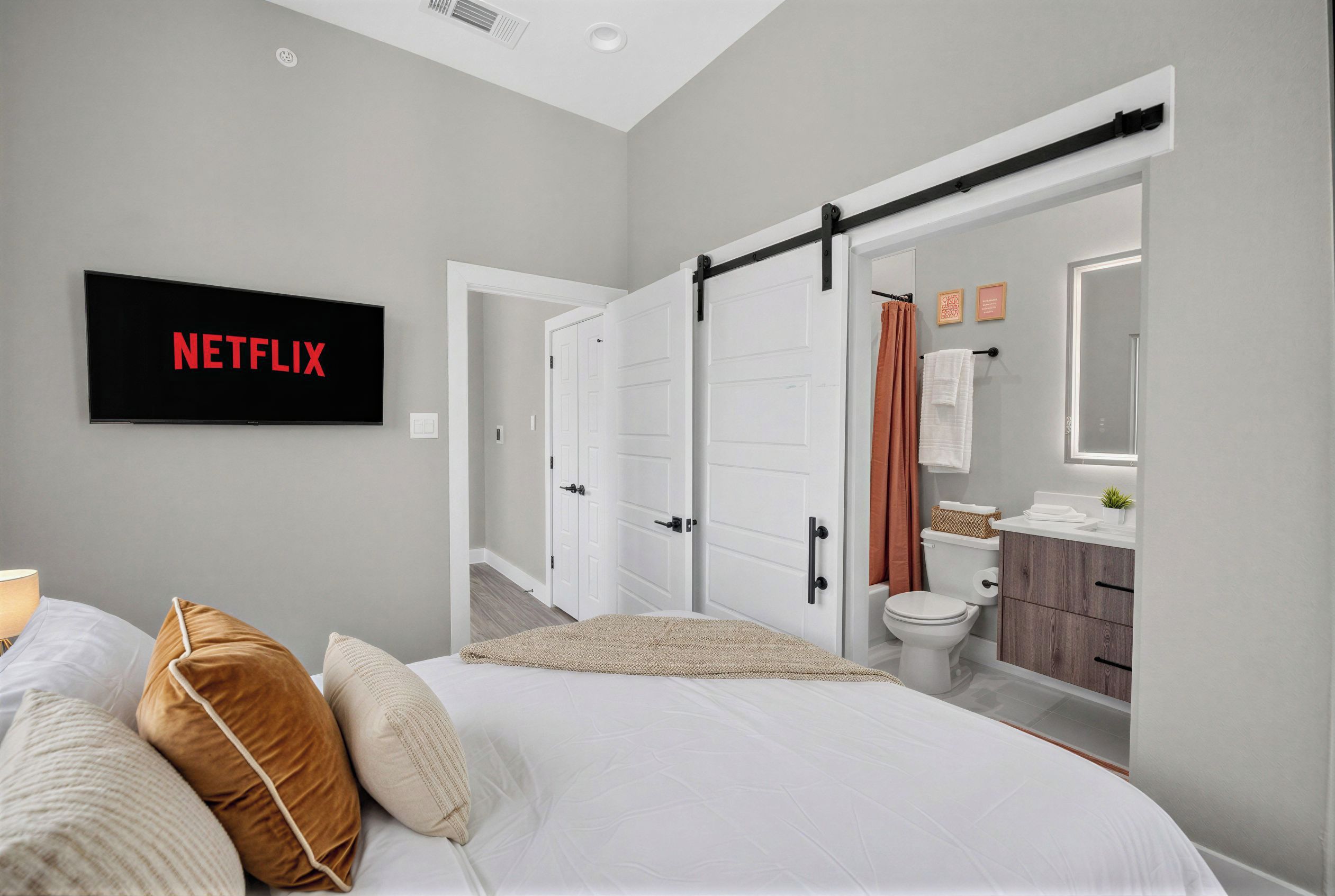 Modern bedroom with ensuite bath, high ceilings, and streaming TV